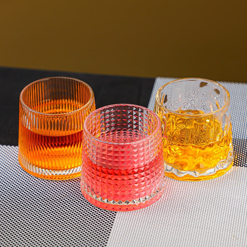 Textured glass tumblers in clear ribbed, diamond-cut, and molten wave styles, each filled with drinks on a modern table setting for dad day.