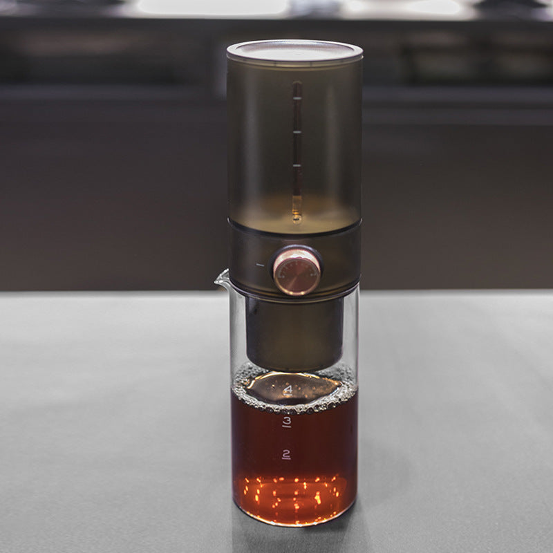 Glass slow drip cold brew coffee maker with ice chamber and carafe, set on a kitchen countertop for homemade cold brew coffee.